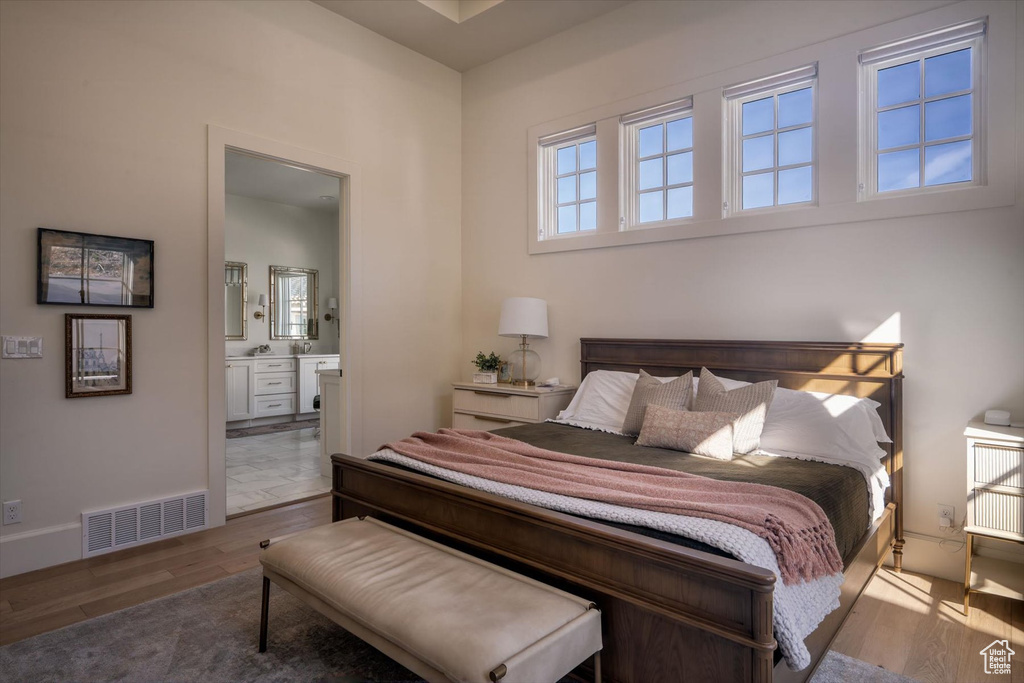 Bedroom with wood finished floors, ensuite bath, and baseboards