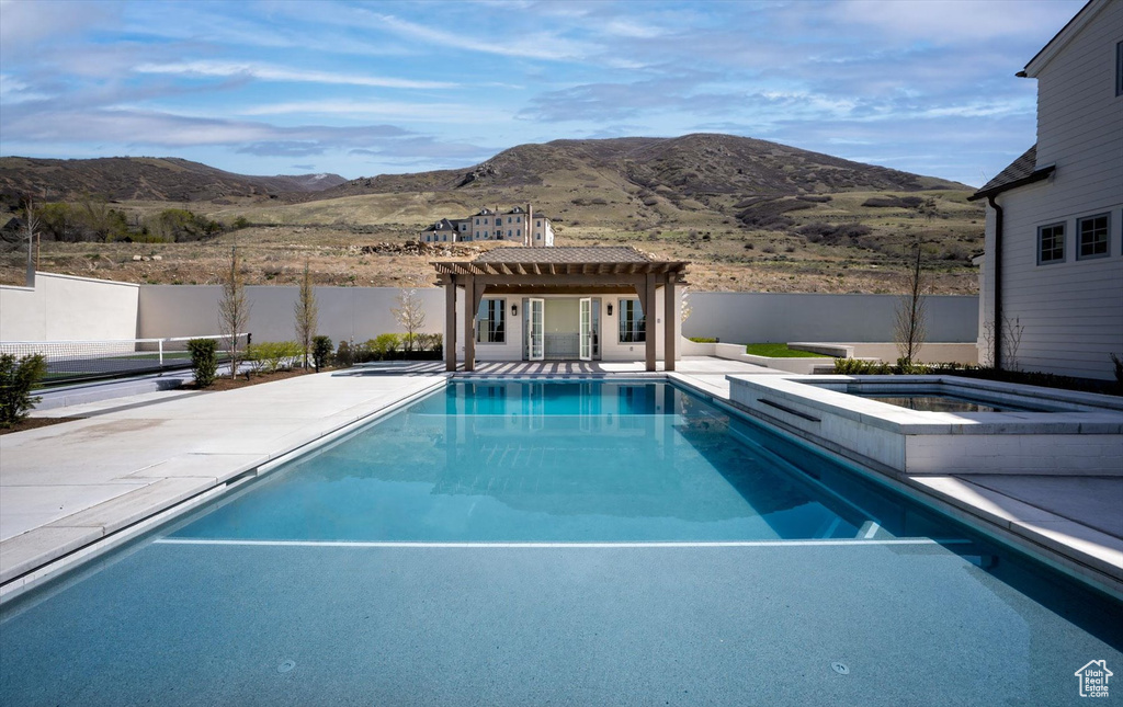 View of swimming pool with a pergola, a mountain view, and a fenced backyard
