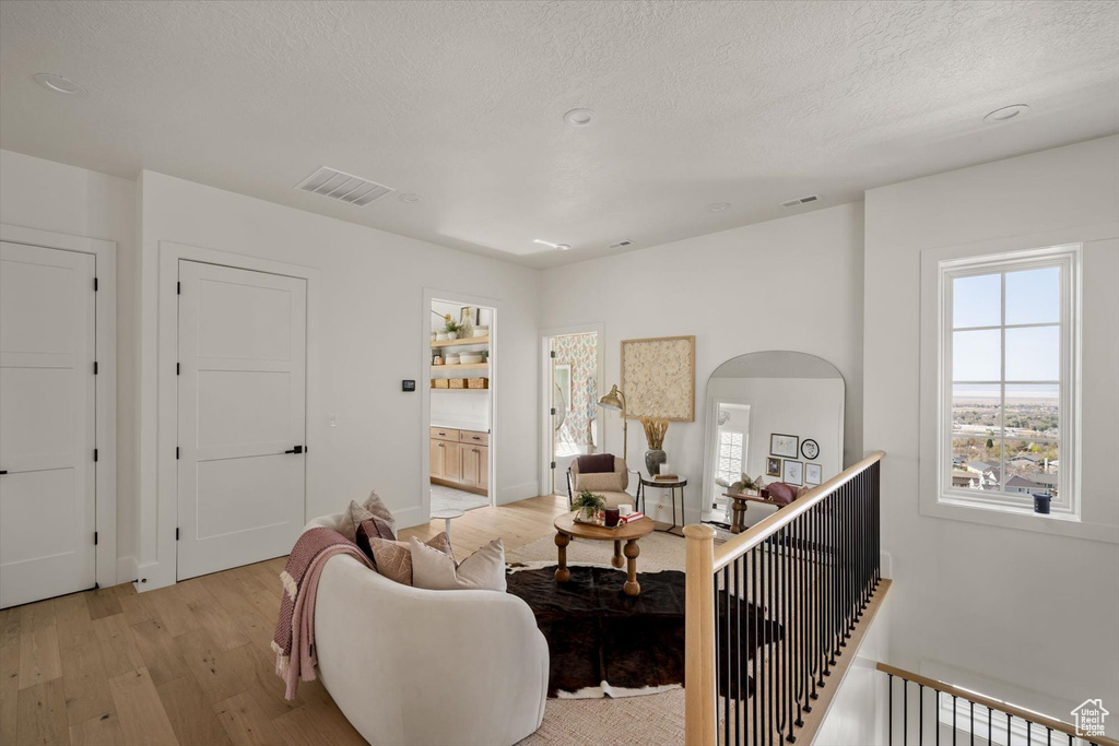 Living room with light wood-style flooring, a textured ceiling, arched walkways, and baseboards