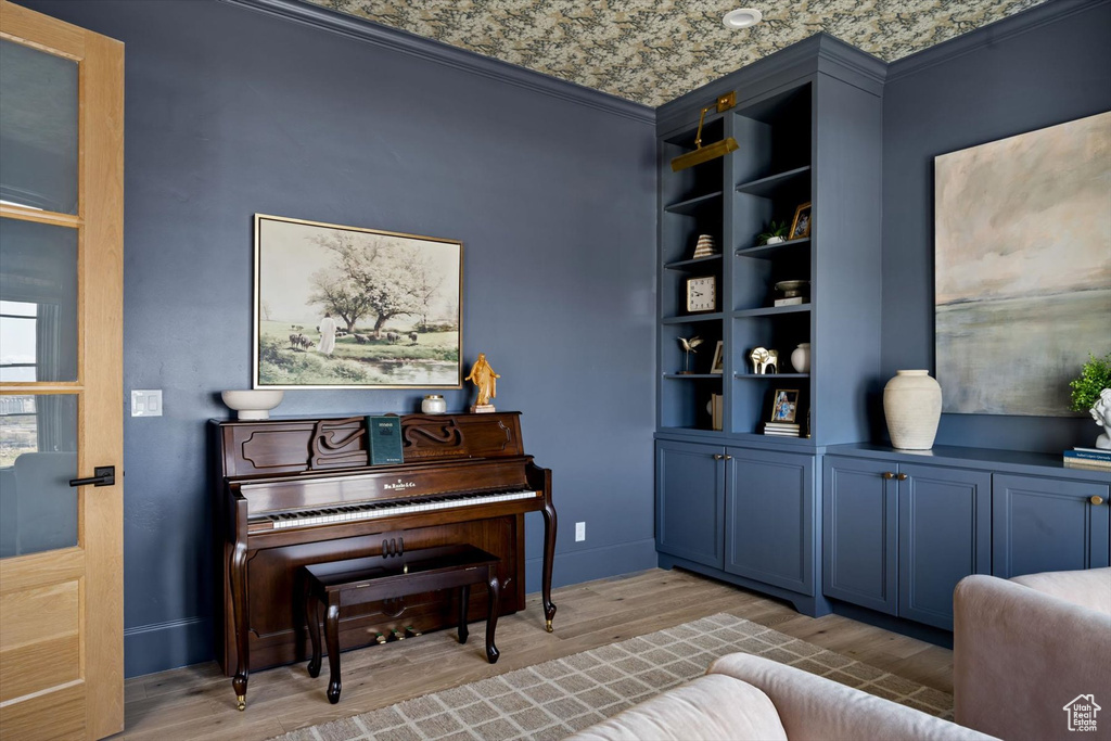 Living area with wood finished floors, crown molding, and baseboards