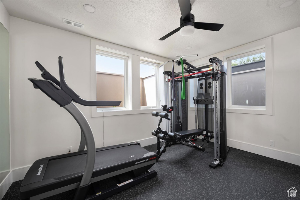 Workout area featuring baseboards, ceiling fan, and a textured ceiling