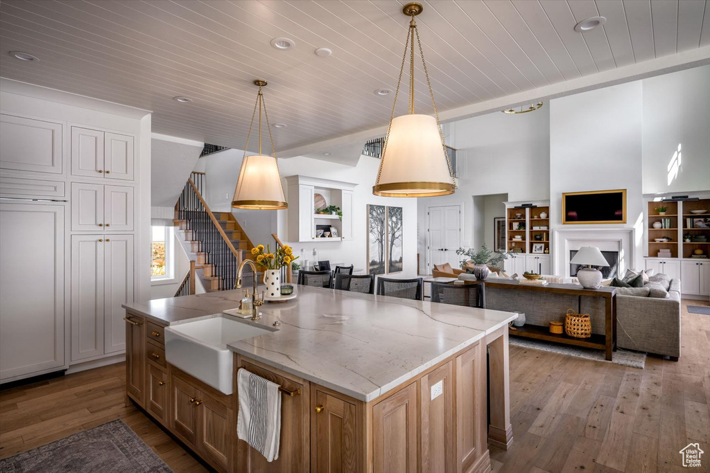 Kitchen featuring wood ceiling, open floor plan, a sink, light wood-type flooring, and pendant lighting