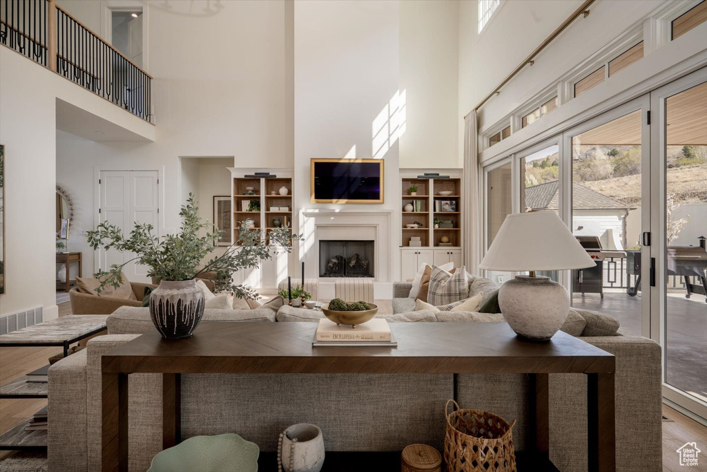 Living area featuring a high ceiling, wood finished floors, and built in shelves