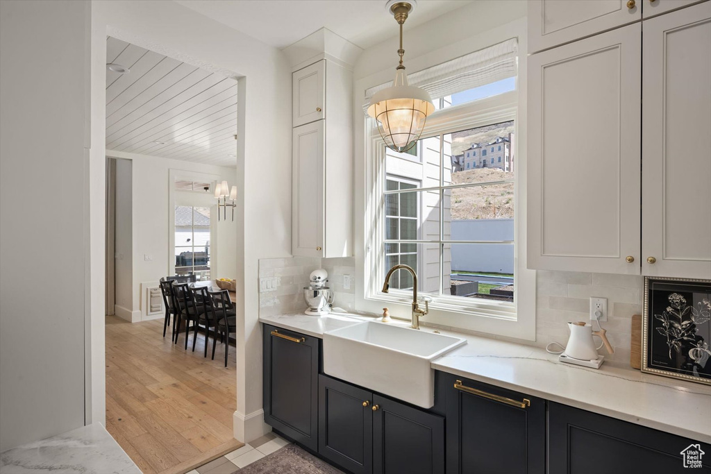 Kitchen featuring a sink, a chandelier, light countertops, tasteful backsplash, and light wood finished floors