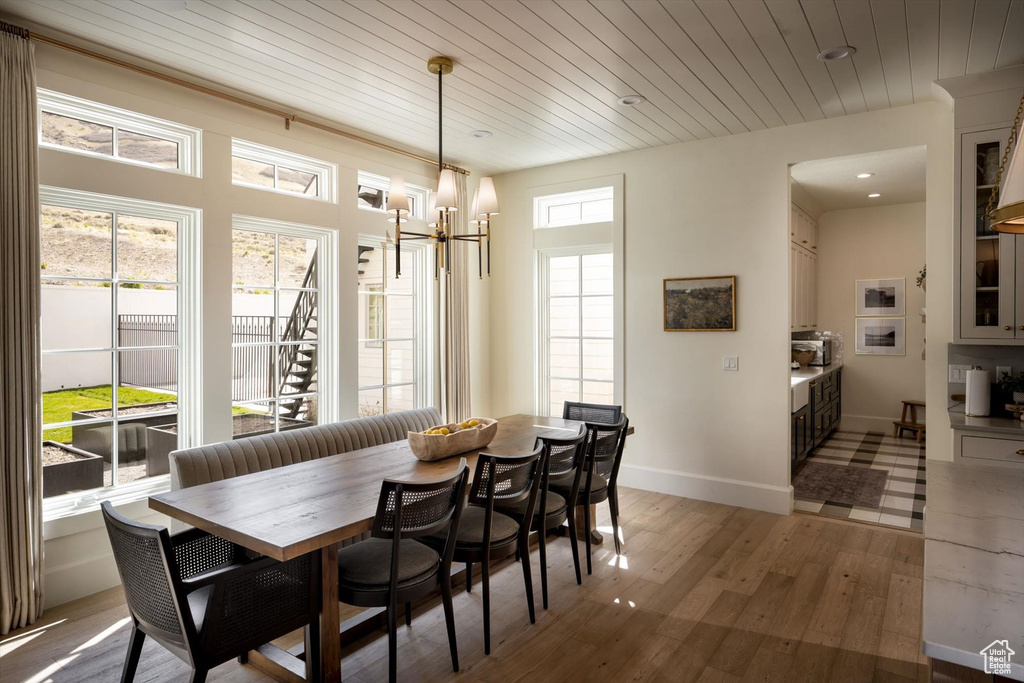 Dining room with light wood-style floors, a chandelier, baseboards, wood ceiling, and recessed lighting