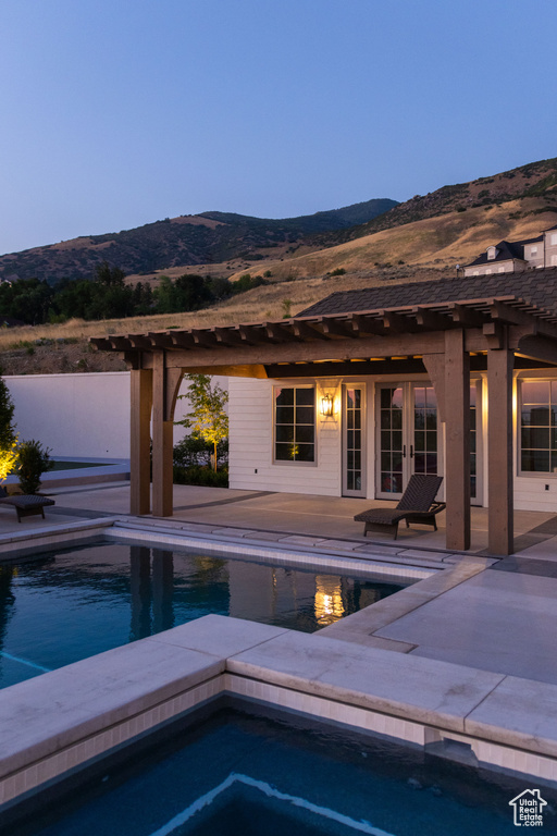 Swimming pool featuring a mountain view, an in-ground hot tub, a patio area, and french doors