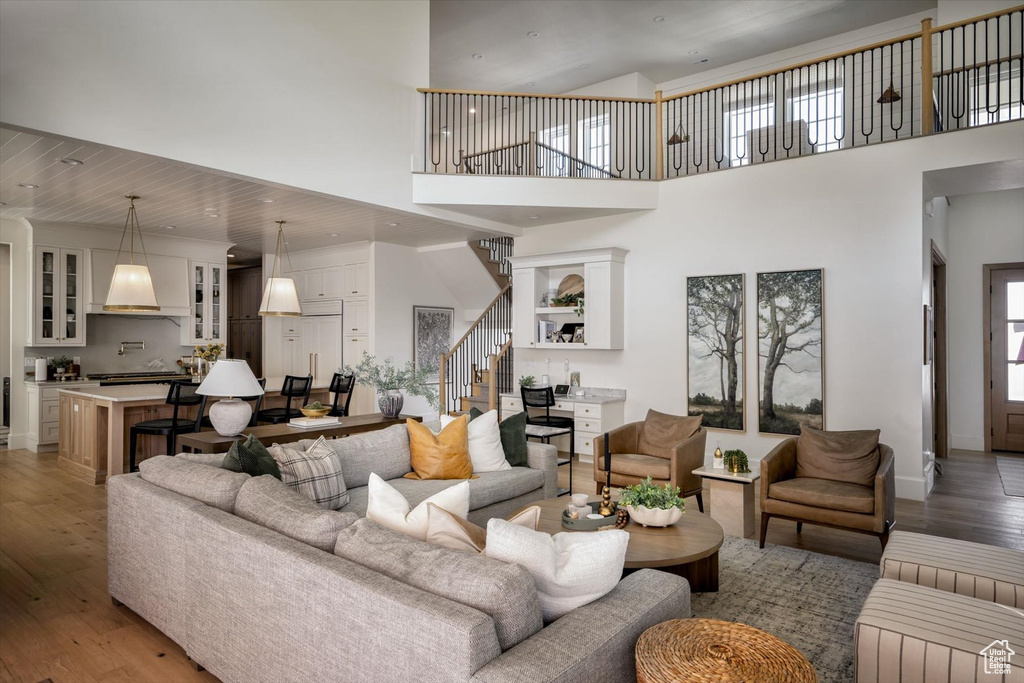 Living room featuring stairs, light wood finished floors, a towering ceiling, and baseboards