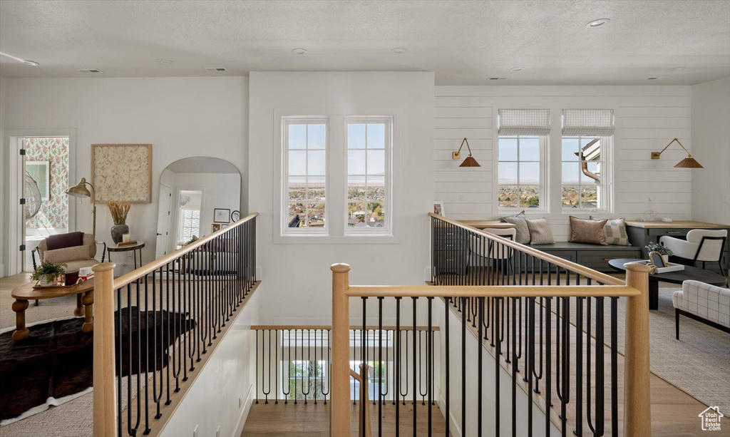 Stairs featuring wood finished floors, plenty of natural light, a textured ceiling, and recessed lighting