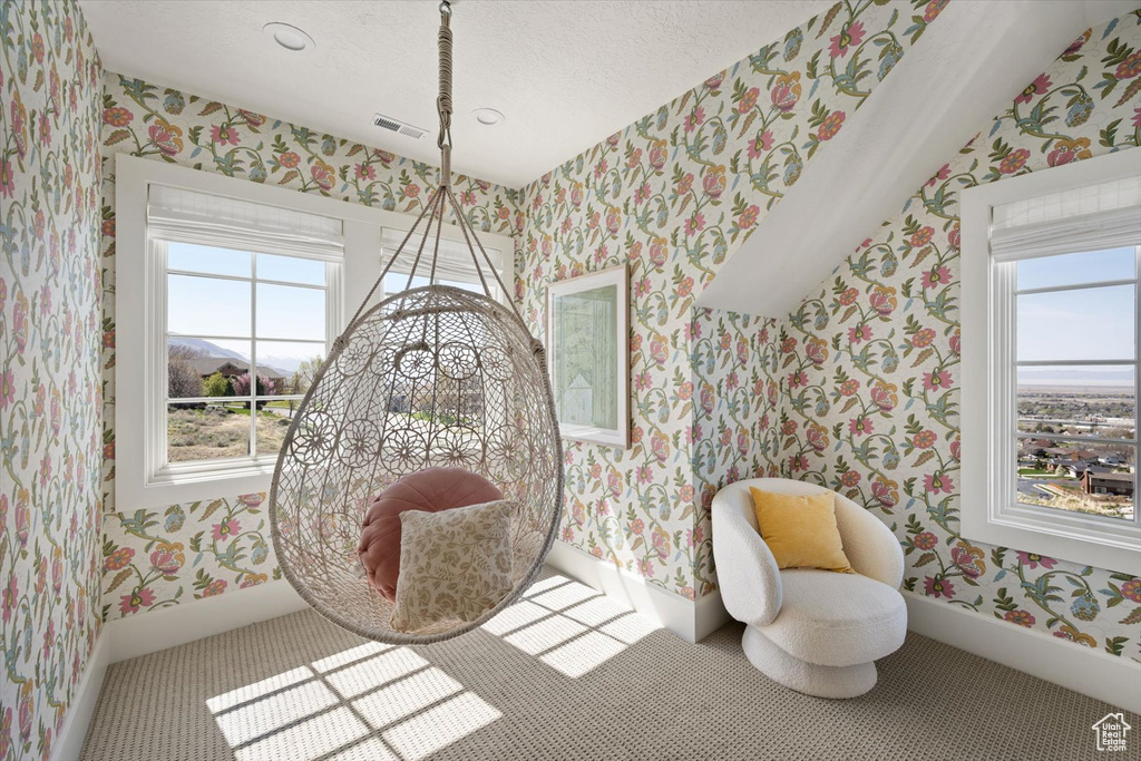 Living area featuring wallpapered walls, healthy amount of natural light, baseboards, and a textured ceiling