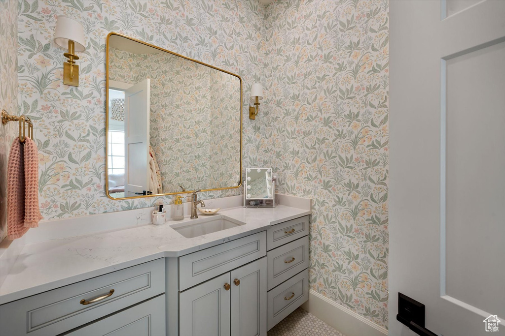 Bathroom with wallpapered walls, baseboards, and vanity