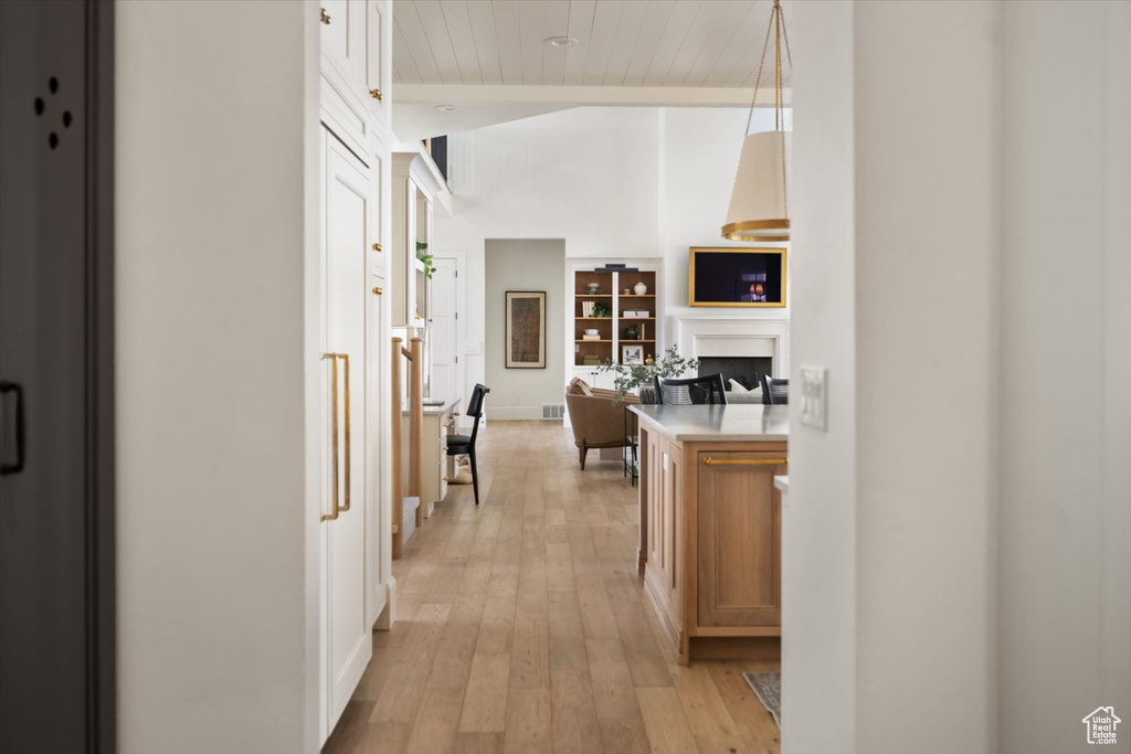 Corridor with light wood-type flooring, wood ceiling, and baseboards