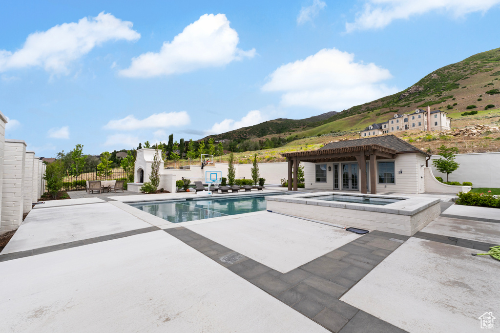 View of pool featuring an in-ground hot tub, a mountain view, fence, a patio area, and a pergola