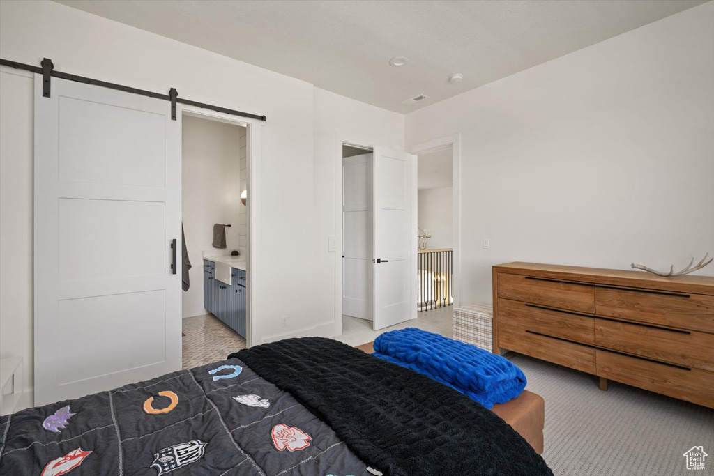Bedroom with a barn door and light carpet