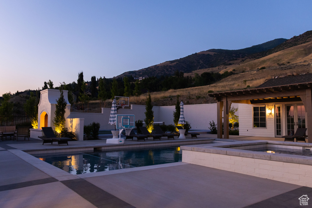 Outdoor pool with a fireplace, a patio area, a mountain view, and an in-ground hot tub