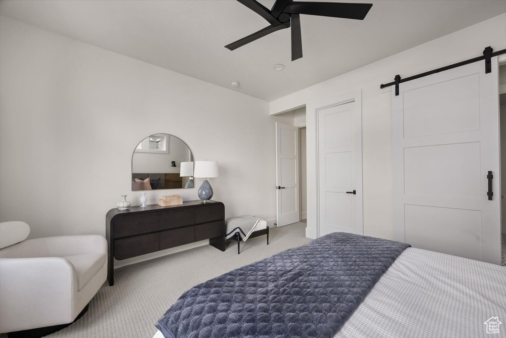 Bedroom featuring a barn door, carpet flooring, and a ceiling fan
