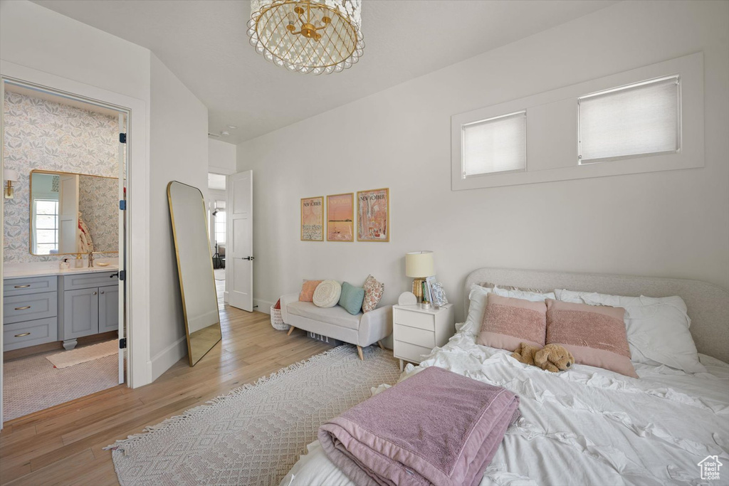 Bedroom featuring light wood-style floors, baseboards, and connected bathroom