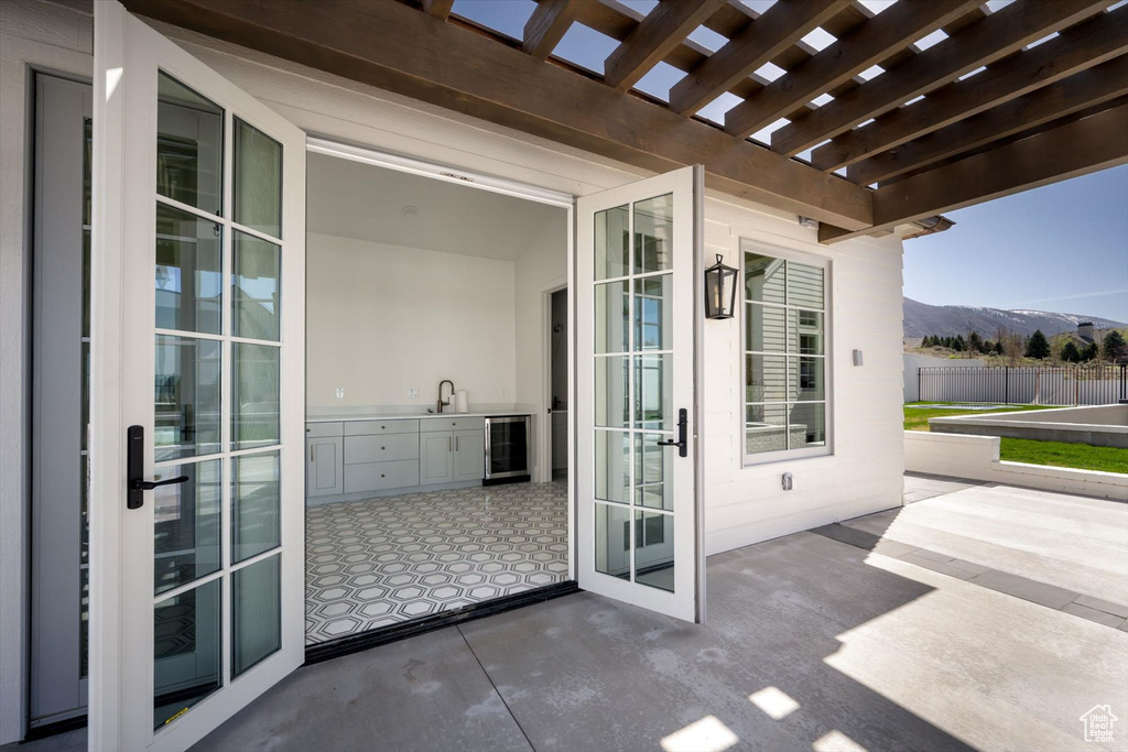 View of patio / terrace with a mountain view, beverage cooler, a pergola, and fence