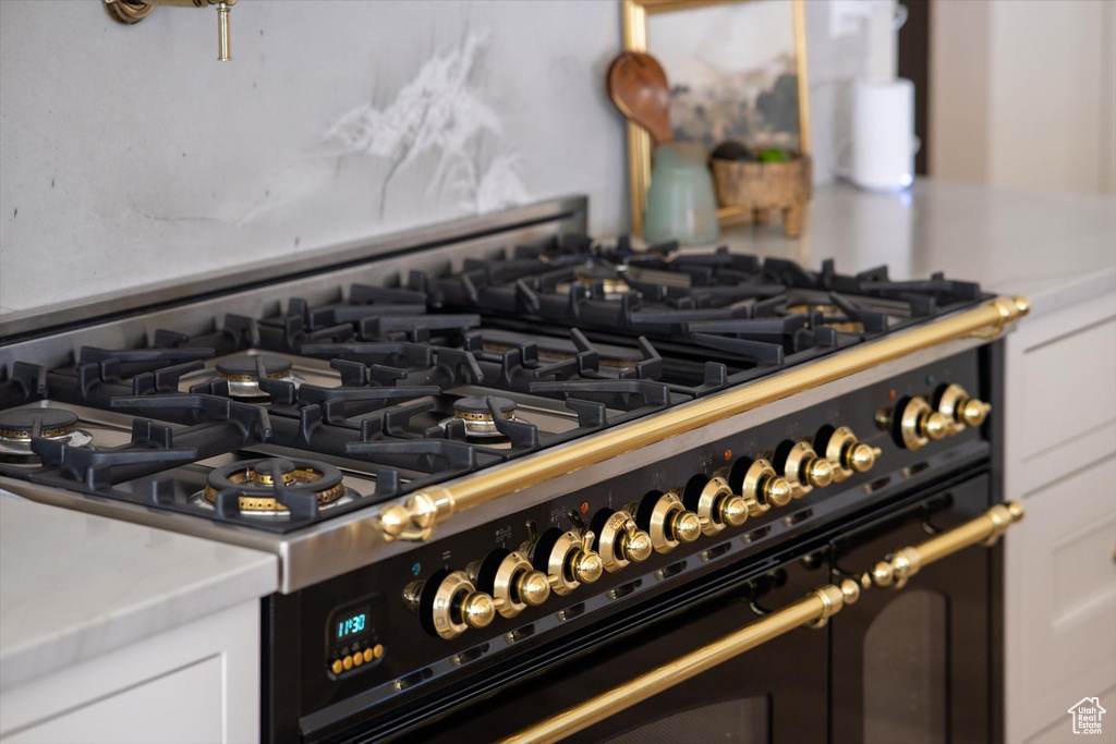 Kitchen view of range with two ovens, light countertops, and white cabinets