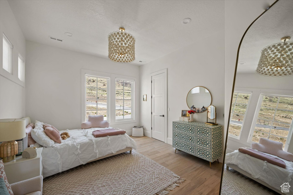Bedroom featuring wood finished floors, a chandelier, and baseboards