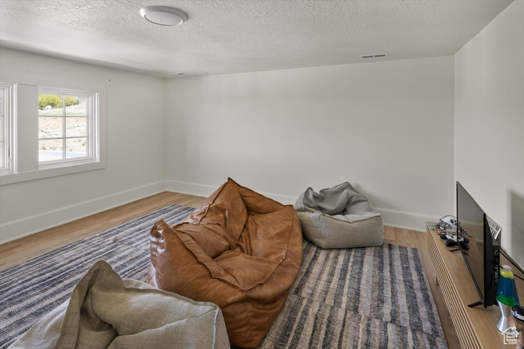 Living room with wood finished floors, a textured ceiling, and baseboards