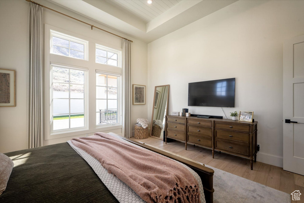 Bedroom featuring wood finished floors, baseboards, a tray ceiling, a towering ceiling, and recessed lighting