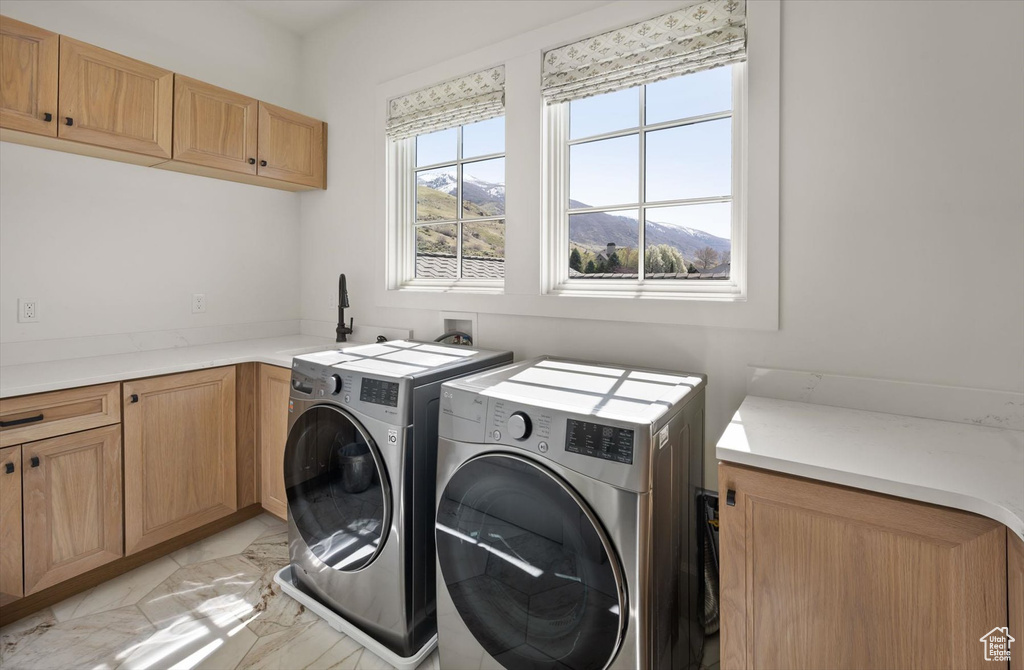 Laundry area featuring washer and clothes dryer, cabinet space, and light marble finish floors