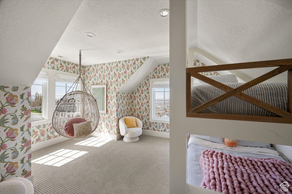 Bedroom with wallpapered walls, a textured ceiling, carpet flooring, baseboards, and multiple windows