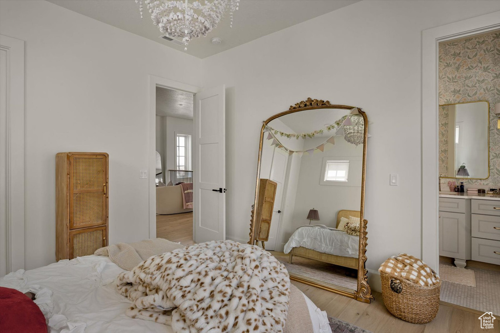Bedroom with light wood finished floors, multiple windows, and a chandelier