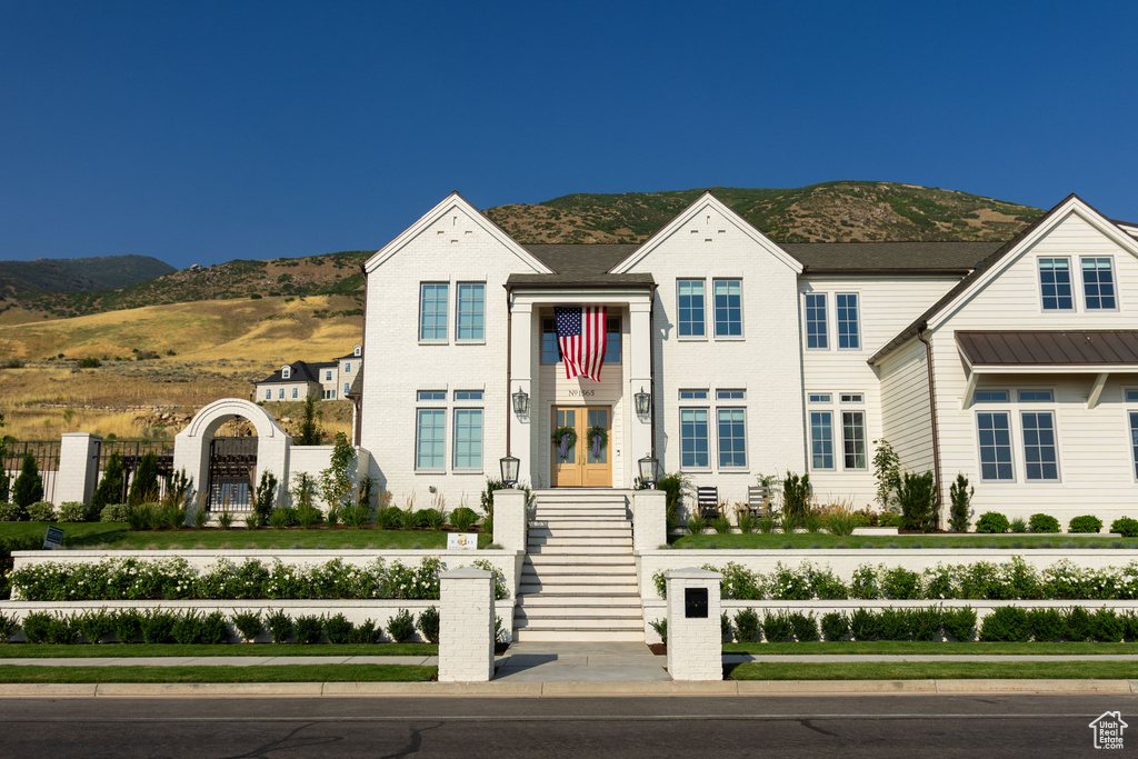View of front of house with a mountain view, fence, and french doors