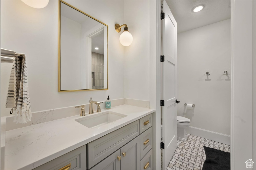 Bathroom featuring vanity, toilet, and baseboards