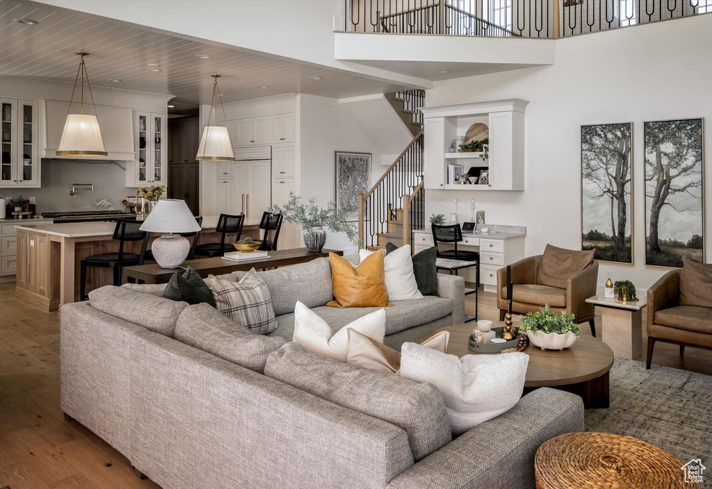 Living area featuring stairs, light wood-style floors, recessed lighting, wood ceiling, and a towering ceiling