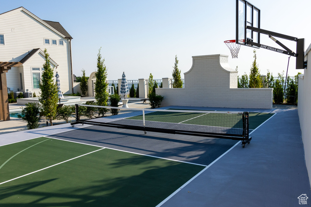 View of sport court with fence, a tennis court, basketball court, and healthy amount of natural light