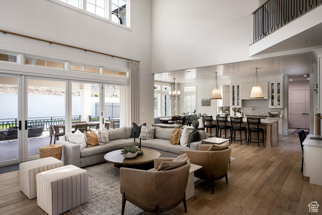 Living room with a towering ceiling, wood finished floors, and a chandelier
