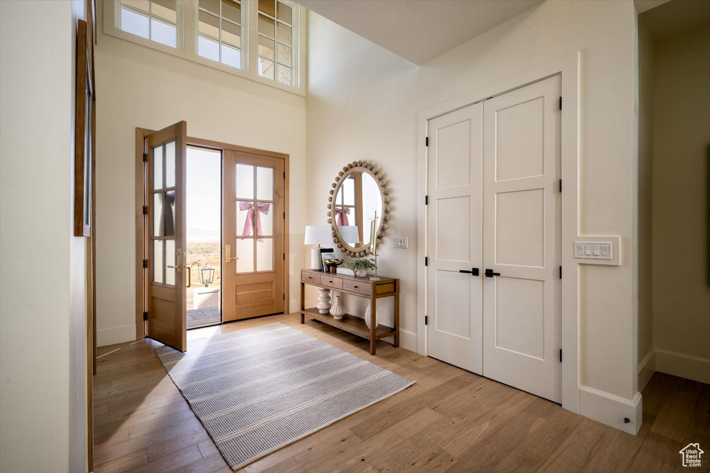 Foyer entrance with wood finished floors, baseboards, and a high ceiling