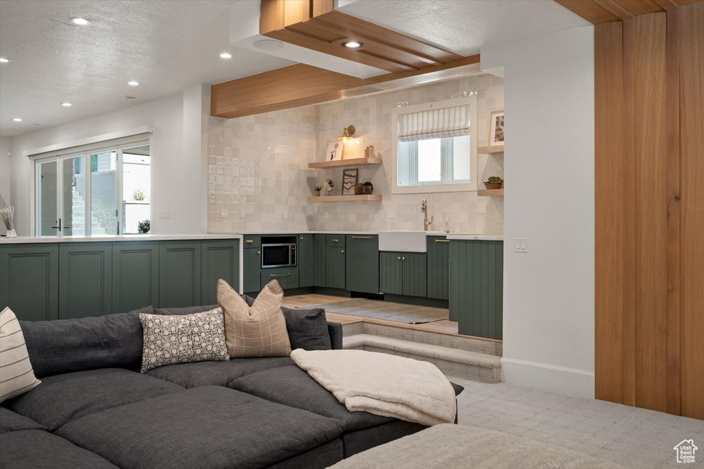 Living room featuring recessed lighting, light colored carpet, wet bar, a textured ceiling, and baseboards