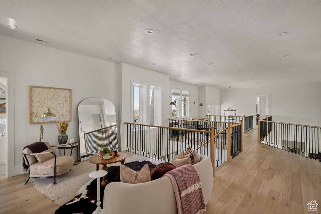 Living area with light wood-style flooring, an upstairs landing, and arched walkways