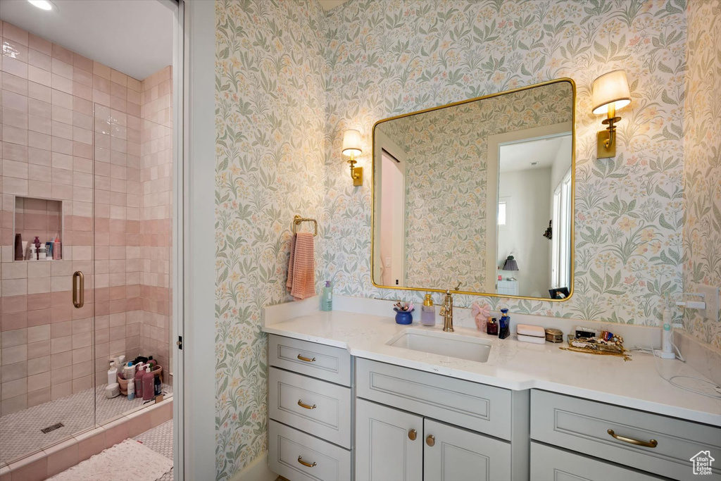 Bathroom with wallpapered walls, a stall shower, and vanity