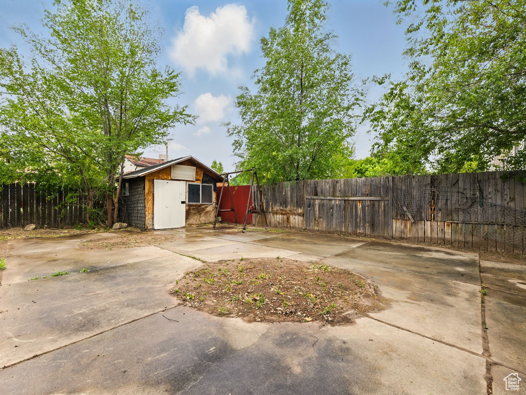 Fenced backyard featuring an outbuilding and a patio area