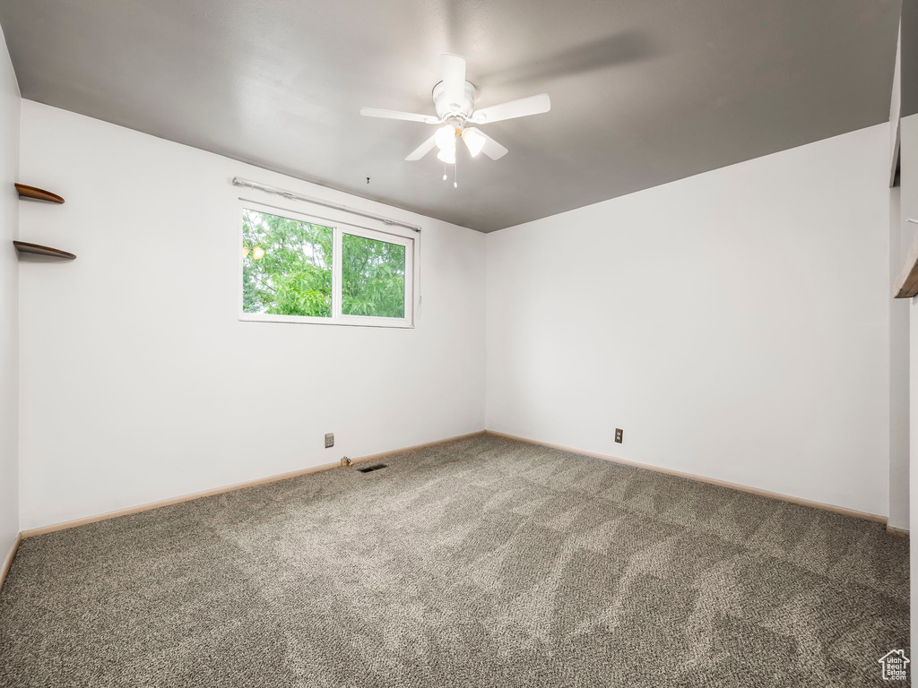 Empty room with carpet, a ceiling fan, and baseboards