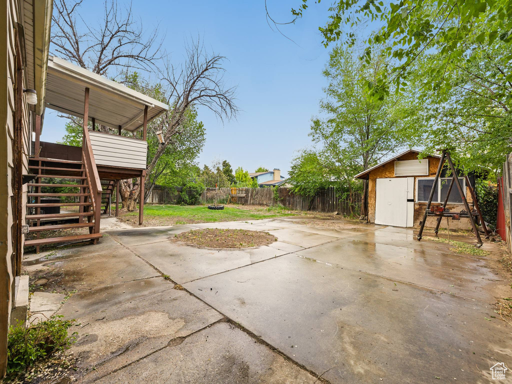 View of patio / terrace featuring stairs, a fenced backyard, a storage unit, an outdoor structure, and a deck