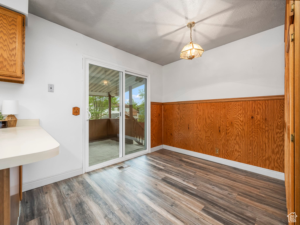 Unfurnished dining area featuring dark wood-style flooring and wainscoting