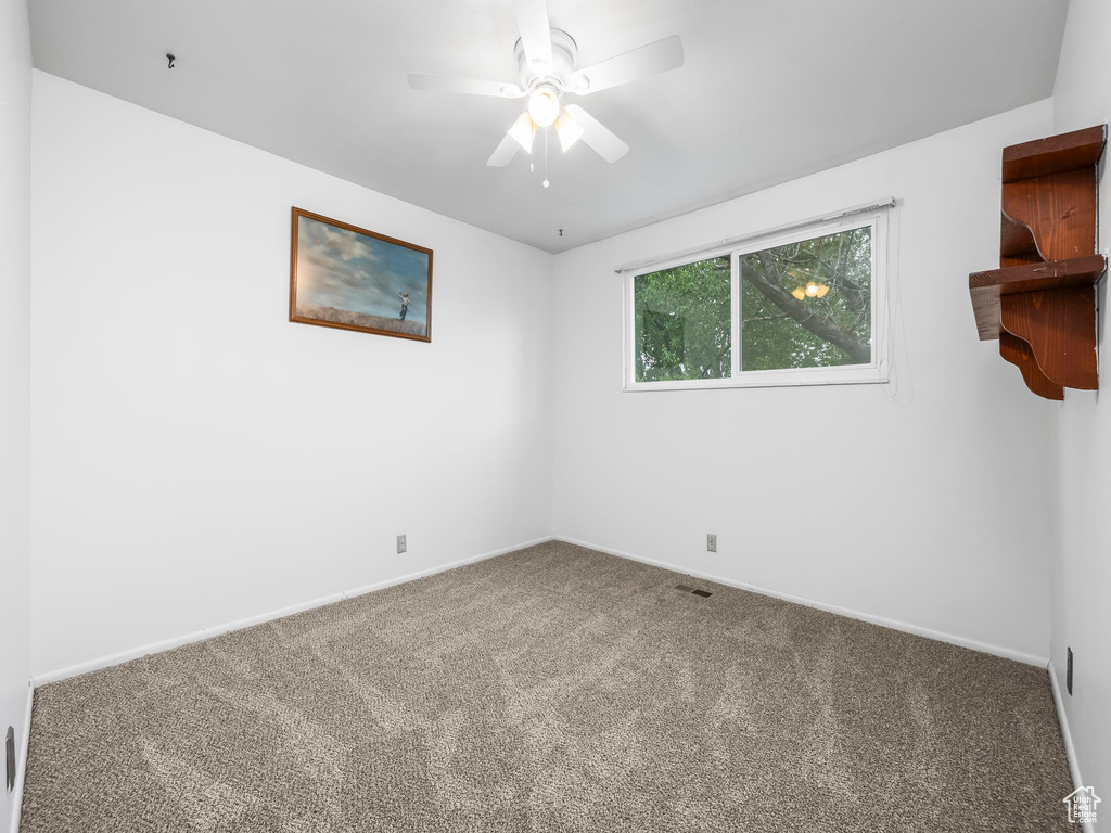 Carpeted spare room with ceiling fan and baseboards
