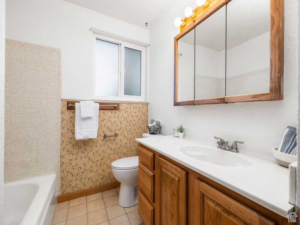 Bathroom featuring tile patterned flooring, a tub, toilet, vanity, and a shower