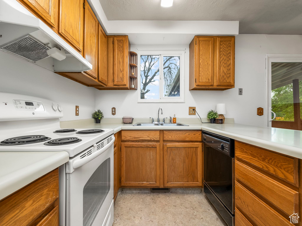 Kitchen featuring electric range, dishwasher, a sink, under cabinet range hood, and brown cabinets