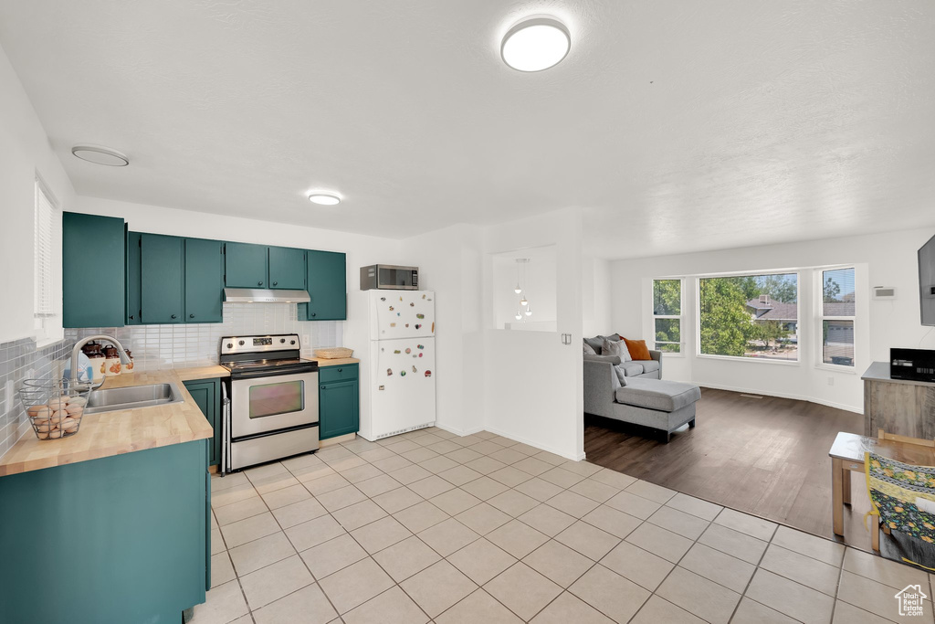Kitchen featuring stainless steel appliances, a sink, backsplash, wood counters, and open floor plan