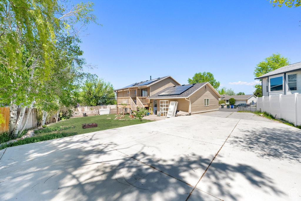 View of front of house featuring concrete driveway and roof mounted solar panels