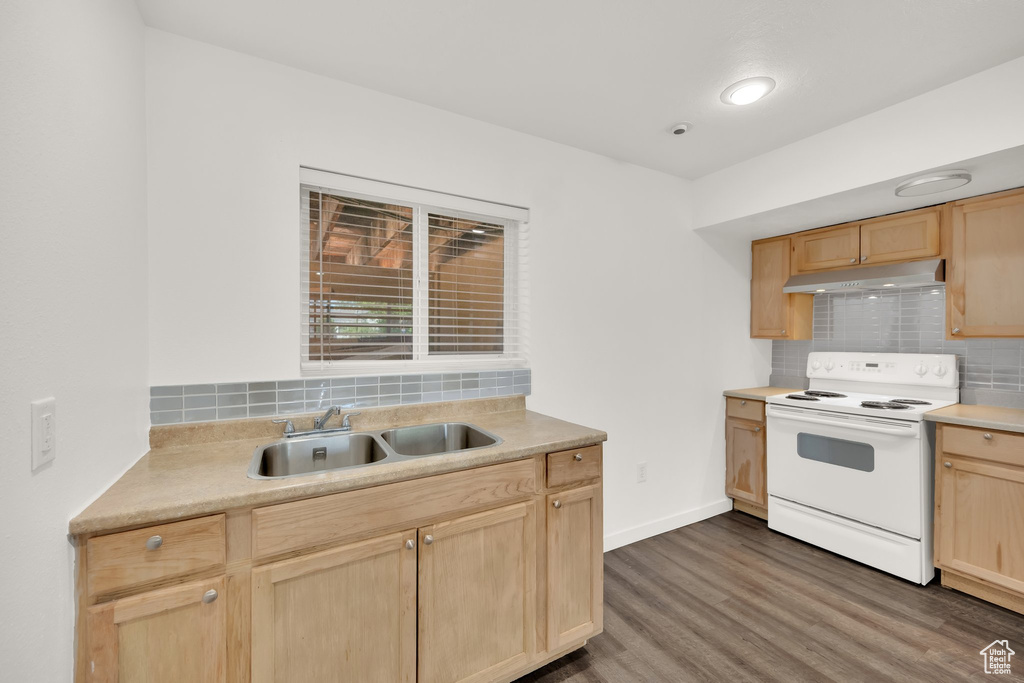 Kitchen with white range with electric stovetop, light brown cabinets, a sink, under cabinet range hood, and wood finished floors