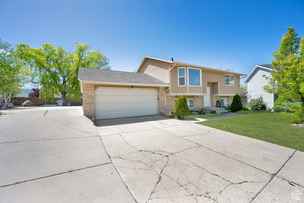 Bi-level home featuring a garage, brick siding, and driveway