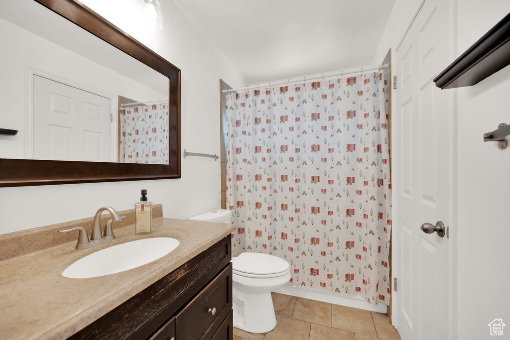 Bathroom featuring vanity, toilet, tile patterned floors, and a shower with curtain