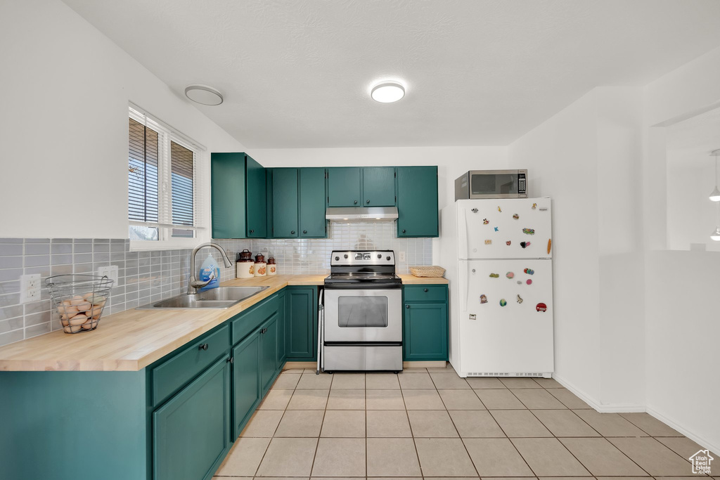 Kitchen featuring stainless steel appliances, a sink, under cabinet range hood, and backsplash